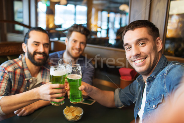 friends with green beer taking selfie at pub Stock photo © dolgachov