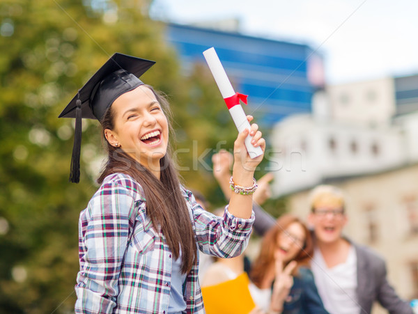 Stock photo: smiling teenage girl in corner-cap with diploma