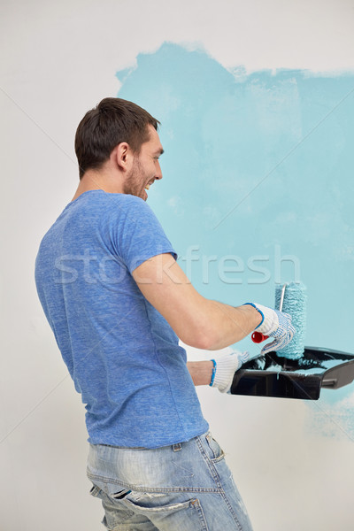 happy man with roller painting wall at home Stock photo © dolgachov