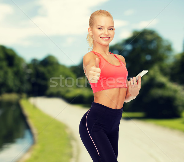 smiling sporty woman with smartphone Stock photo © dolgachov