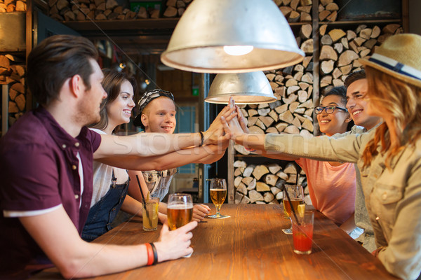 happy friends with drinks making high five at bar Stock photo © dolgachov