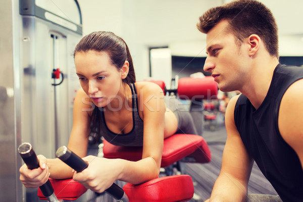 young woman with trainer exercising on gym machine Stock photo © dolgachov