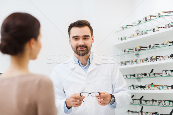 woman and optician showing glasses at optics store Stock photo © dolgachov
