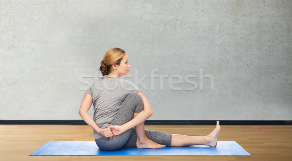 woman making yoga in twist pose on mat Stock photo © dolgachov