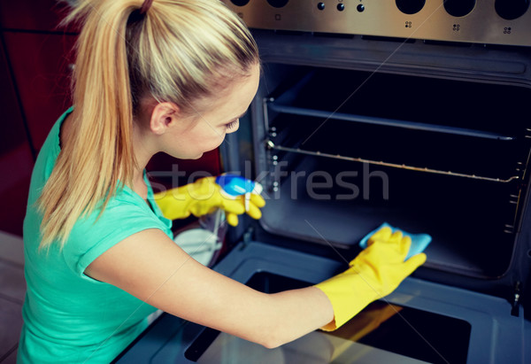 happy woman cleaning cooker at home kitchen Stock photo © dolgachov