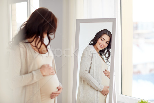 happy pregnant woman looking to mirror at home Stock photo © dolgachov