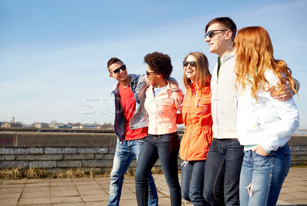 happy teenage friends walking along city street Stock photo © dolgachov