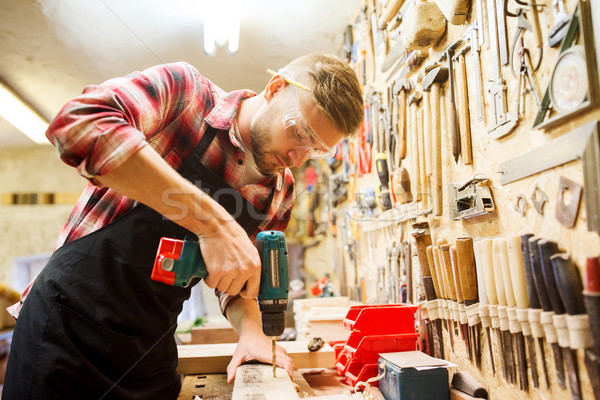 Stock photo: carpenter with drill drilling plank at workshop