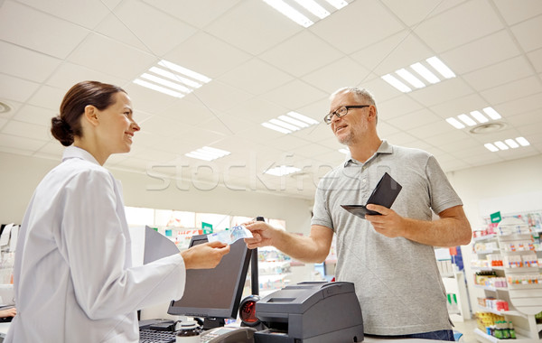 senior man giving money to pharmacist at drugstore Stock photo © dolgachov