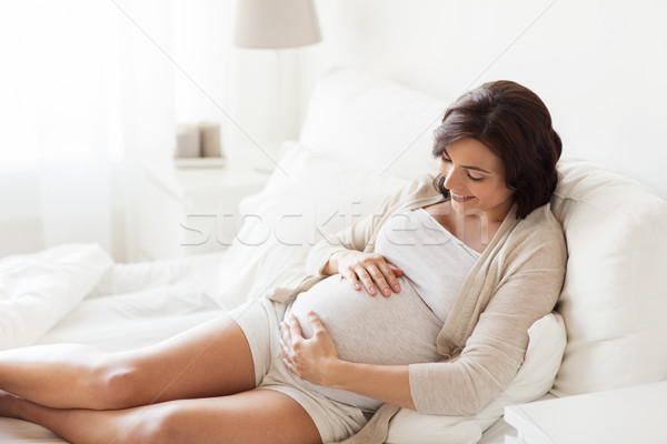 happy pregnant woman lying on bed at home Stock photo © dolgachov