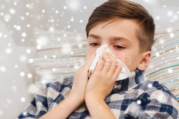 close up of ill boy lying in bed and blowing nose Stock photo © dolgachov