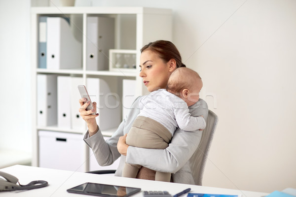 businesswoman with baby and smartphone at office Stock photo © dolgachov