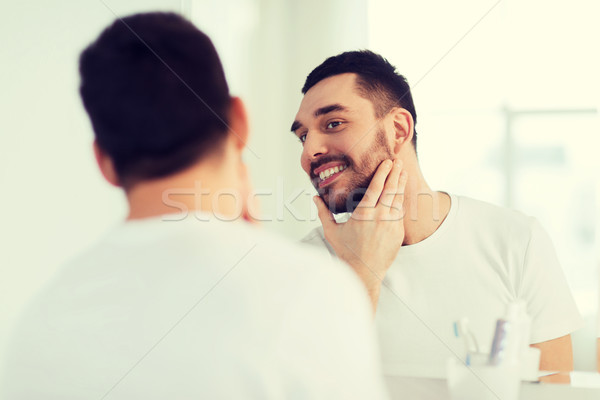 Heureux jeune homme regarder miroir maison salle de bain [[stock_photo]] © dolgachov