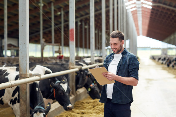 Stock photo: farmer with clipboard and cows in cowshed on farm