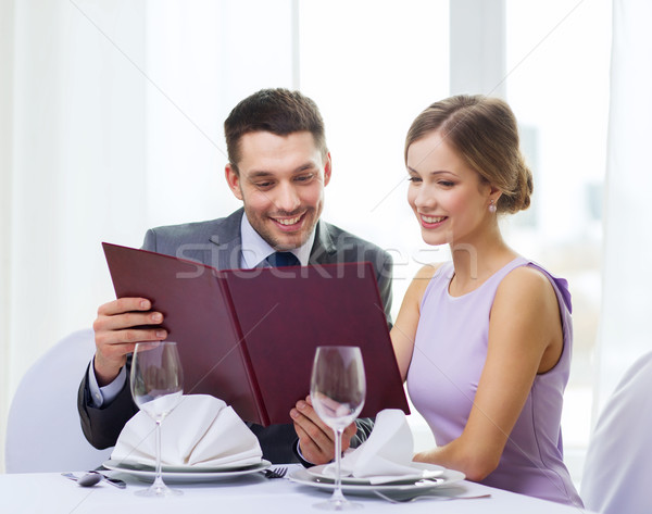 smiling couple with menu at restaurant Stock photo © dolgachov