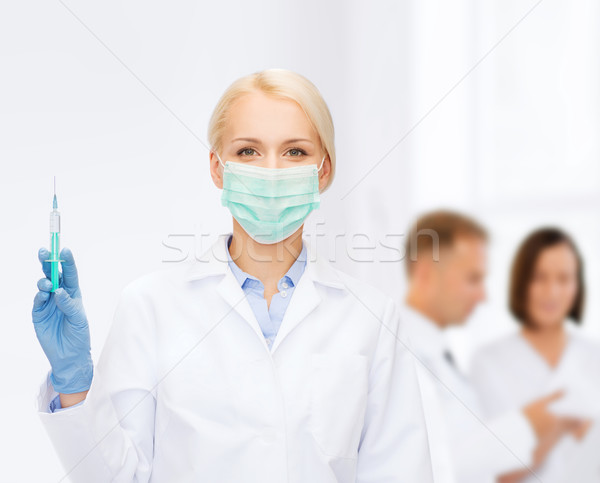 doctor in mask holding syringe with injection Stock photo © dolgachov