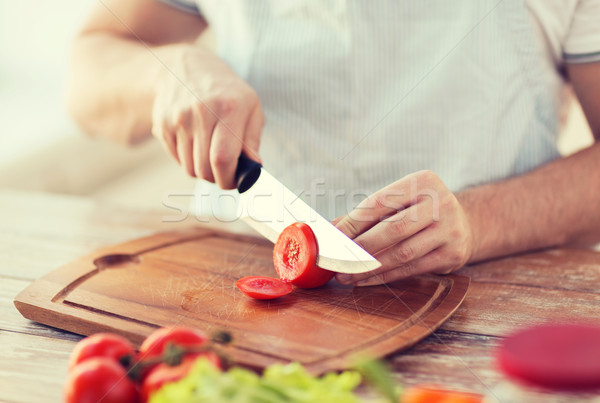 Stock photo: male hand cutting tomato on board with knife