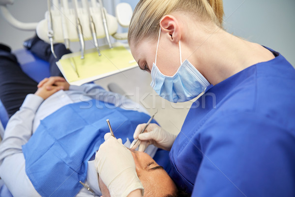 female dentist in mask checking male patient teeth Stock photo © dolgachov