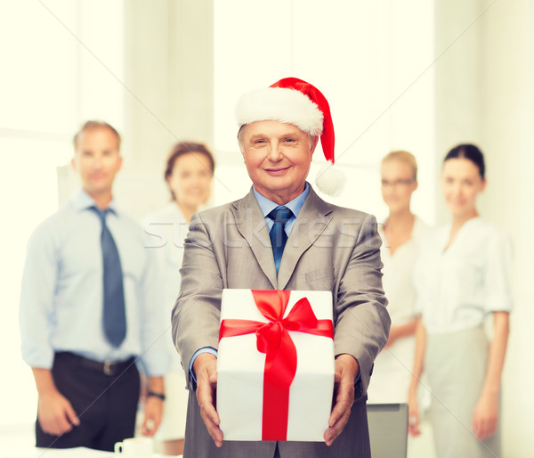 smiling man in suit and santa helper hat with gift Stock photo © dolgachov