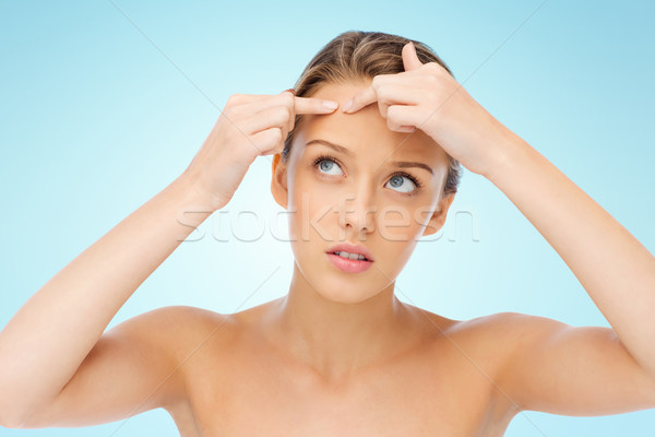 young woman squeezing pimple on her face Stock photo © dolgachov