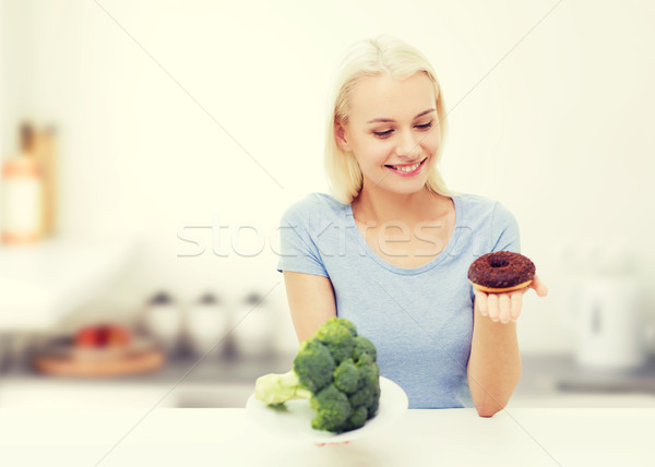 Stock photo: smiling woman with broccoli and donut on kitchen