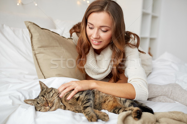 Stock photo: happy young woman with cat lying in bed at home