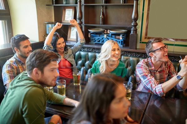 Stock photo: friends with beer watching football at bar or pub