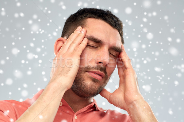 unhappy man suffering from head ache over snow Stock photo © dolgachov