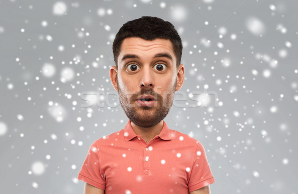 surprised man in polo t-shirt over snow background Stock photo © dolgachov
