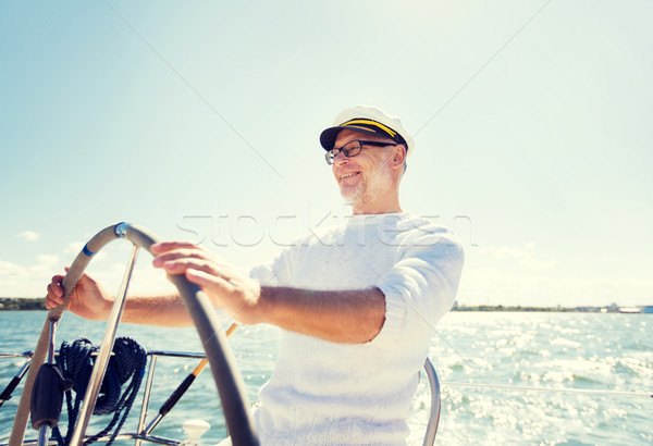 senior man at helm on boat or yacht sailing in sea Stock photo © dolgachov