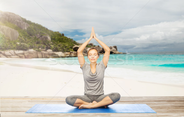 woman meditating in yoga lotus pose on beach Stock photo © dolgachov