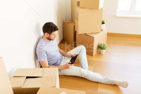 man with tablet pc and boxes moving to new home Stock photo © dolgachov