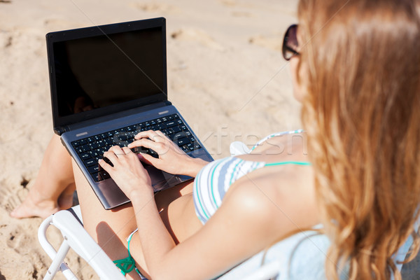 Stock photo: girl looking at laptop on the beach