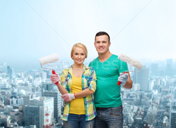 smiling couple in gloves with paint rollers Stock photo © dolgachov