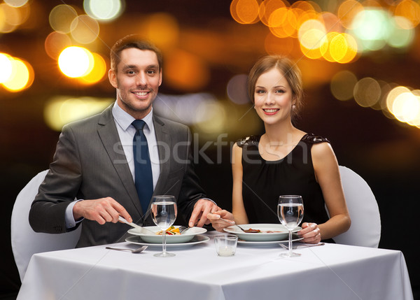 smiling couple eating main course at restaurant Stock photo © dolgachov