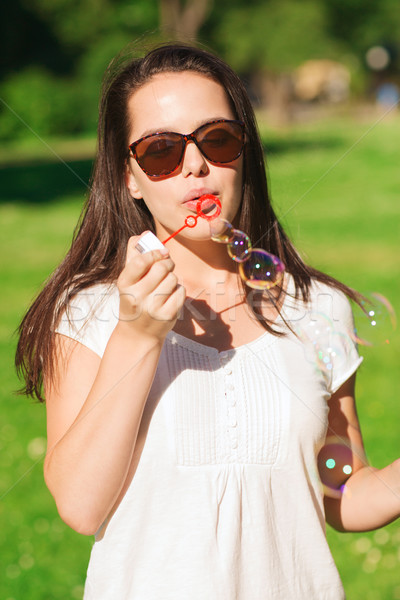 Stock photo: smiling young girl with soap bubbles in park