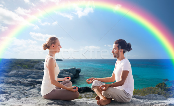 happy couple meditating in lotus pose on beach Stock photo © dolgachov
