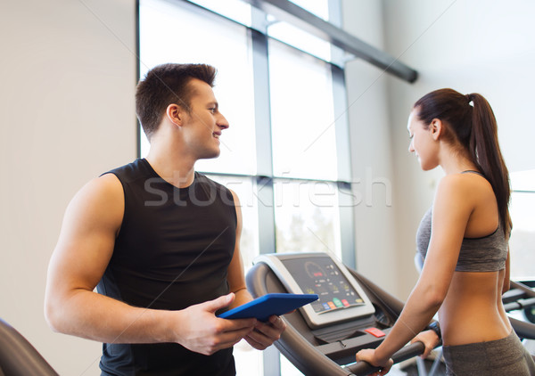 Stock photo: happy woman with trainer on treadmill in gym