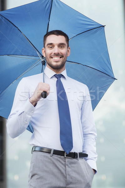 young smiling businessman with umbrella outdoors Stock photo © dolgachov