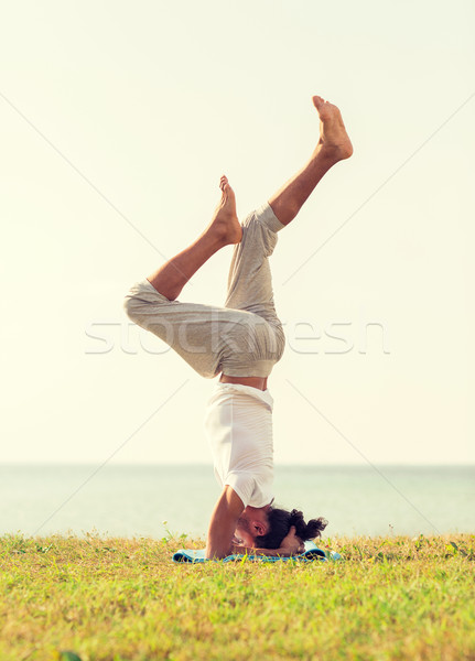 man making yoga exercises outdoors Stock photo © dolgachov