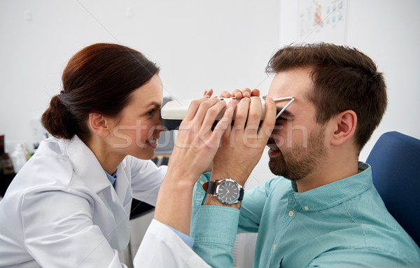 optician with pupilometer and patient at eye clinic Stock photo © dolgachov