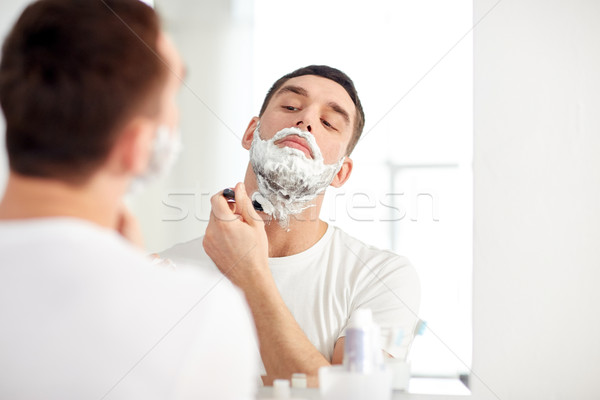 man shaving beard with razor blade at bathroom Stock photo © dolgachov