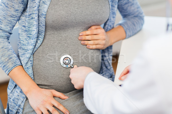doctor with stethoscope and pregnant woman belly Stock photo © dolgachov