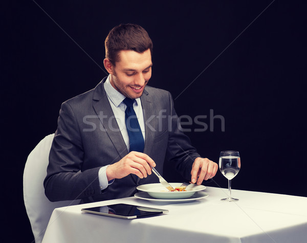 smiling man with tablet pc eating main course Stock photo © dolgachov