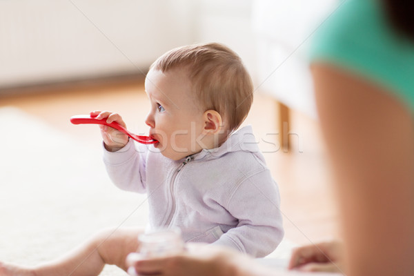 mother and baby with spoon eating at home Stock photo © dolgachov