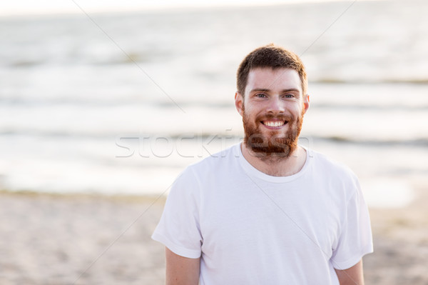happy smiling young man with red beard on beach Stock photo © dolgachov