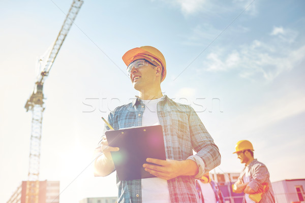 builder in hardhat with clipboard at construction Stock photo © dolgachov