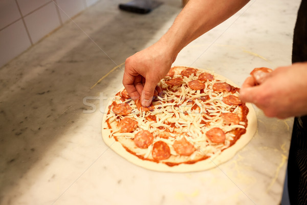 cook hands adding salami to pizza at pizzeria Stock photo © dolgachov