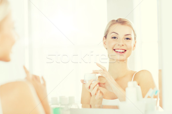 Heureux femme crème visage salle de bain [[stock_photo]] © dolgachov