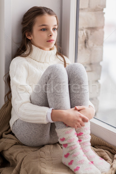 sad girl sitting on sill at home window in winter Stock photo © dolgachov